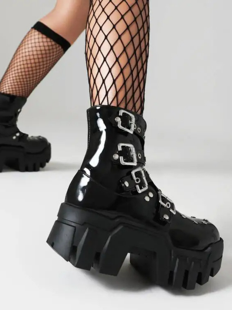 Rebel Core Ankle Platform Boots come in a patent vegan leather construction, with a treaded chunky heeled platform, buckle straps and eyelet details.